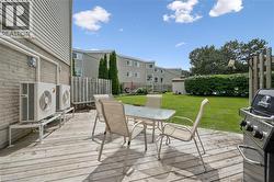 Expansive backyard featuring a wood deck leading to community pool, manicured lawn, and mature privacy hedging - 