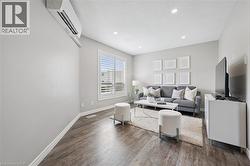 Living area featuring wood-finish flooring, recessed lighting, and a wall-mounted climate control unit - 