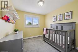 Room featuring a light yellow wall color, gray carpet, and white baseboards - 