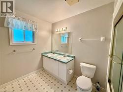 Bathroom featuring a double vanity with integrated sinks, a mirror with overhead lighting, a window, and patterned flooring - 