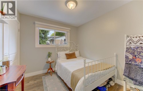 Bright room featuring a window with white trim, wood-finish flooring, light neutral wall paint, and white baseboards - 127 Strathcona Crescent, Kitchener, ON 