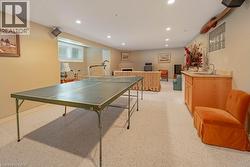 Spacious recreation room featuring recessed lighting, a built-in wet bar with a countertop sink, and light-toned carpeting - 