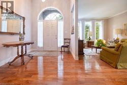 Inviting entryway featuring wood-finish flooring, a paneled front door with an arched transom, and sidelight windows - 