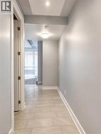 Hallway featuring light-toned plank tile flooring, recessed ceiling lighting, a flush mount light fixture, white baseboards, and a light gray wall finish - 