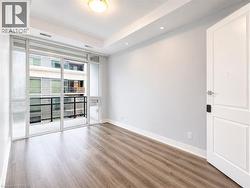 Room featuring wood-finish flooring, a tray ceiling with recessed lighting, and a full-light door opening to a private balcony with metal railings - 