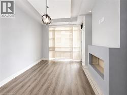 Contemporary interior featuring wood-finish flooring, a modern fireplace, recessed lighting, a decorative pendant light fixture, and roller shades - 