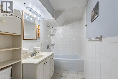 Bathroom featuring white tile walls, a built-in bathtub, and a vanity with a drop-in sink - 1293 Daimler Road, Mississauga, ON 