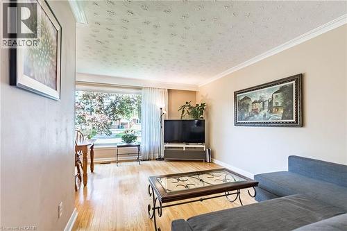 Spacious living area featuring light wood-finish flooring, a large picture window, crown molding, and neutral wall tones - 1293 Daimler Road, Mississauga, ON 