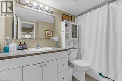 Bathroom featuring a single vanity with a laminate countertop, undermount sink, and a large wall-mounted mirror - 