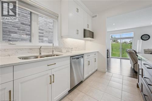 Kitchen featuring white cabinetry with gold-toned hardware, a double basin sink, and stainless steel dishwasher - 153 Rivertrail Avenue, Kitchener, ON - Indoor Photo Showing Kitchen With Double Sink
