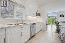 Kitchen featuring white cabinetry with gold-toned hardware, a double basin sink, and stainless steel dishwasher - 