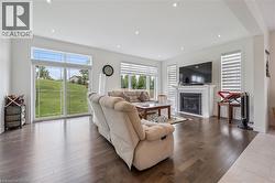 Spacious living area featuring dark wood-finish flooring, recessed lighting, and a white-mantled fireplace - 