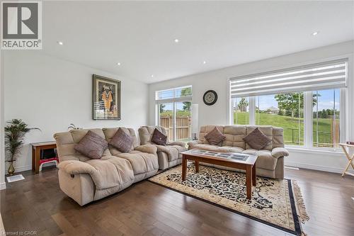 Spacious living area featuring large windows with horizontal blinds, recessed ceiling lighting, and dark wood-finish flooring - 153 Rivertrail Avenue, Kitchener, ON - Indoor Photo Showing Living Room