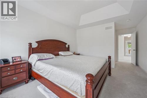 Carpeted bedroom featuring a tray ceiling, white walls, and a doorway leading to another area - 153 Rivertrail Avenue, Kitchener, ON - Indoor Photo Showing Bedroom