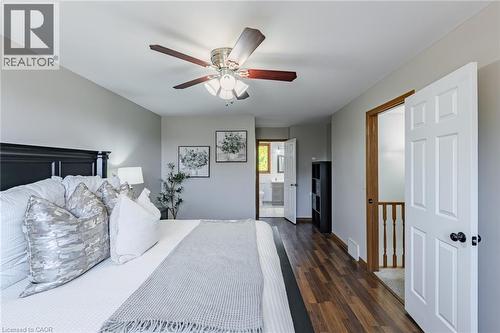 Bedroom featuring wood-finish flooring, a ceiling fan with integrated lighting, and a white six-panel door - 141 Lynndale Road, Simcoe, ON 