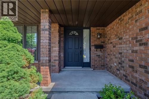 Brick exterior featuring a dark entry door with arched lites, a transom window, and a side lite - 141 Lynndale Road, Simcoe, ON 
