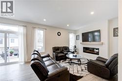 Living area featuring light wood-type flooring, recessed lighting, and a glass covered fireplace - 