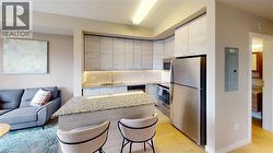 Open-concept living area featuring a kitchen with light wood-finish cabinetry, stainless steel appliances, granite countertops, and an island with bar seating - 