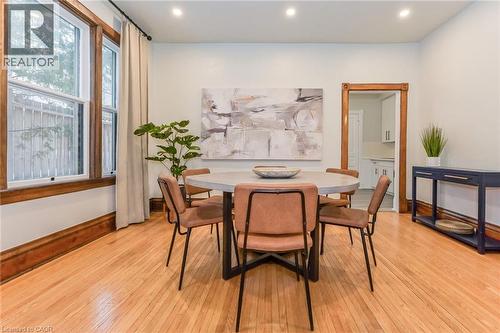 Open-concept dining area featuring wood-finish flooring, a wood-trimmed window, recessed lighting, and a wood-trimmed doorway - 67 Ahrens Street W, Kitchener, ON 