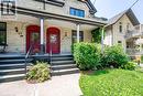 Brick exterior with red arched entry doors and a covered porch - 67 Ahrens Street W, Kitchener, ON 