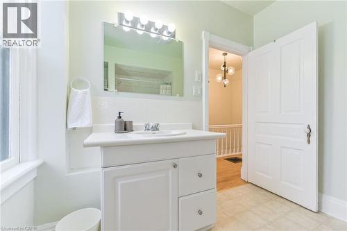 Bathroom featuring a white vanity with integrated sink, chrome faucet, and a large mirror with overhead lighting - 67 Ahrens Street W, Kitchener, ON 