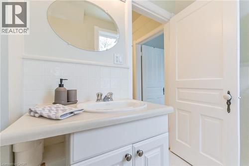 White vanity with an integrated sink and chrome faucet, complemented by a large oval mirror - 67 Ahrens Street W, Kitchener, ON 