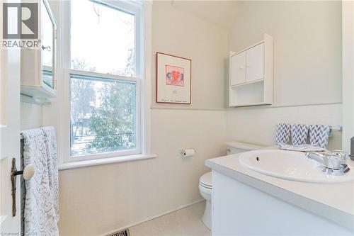 Bright bathroom featuring a single-pane window, white vanity with integrated sink, chrome faucet, and built-in wall cabinetry - 67 Ahrens Street W, Kitchener, ON 