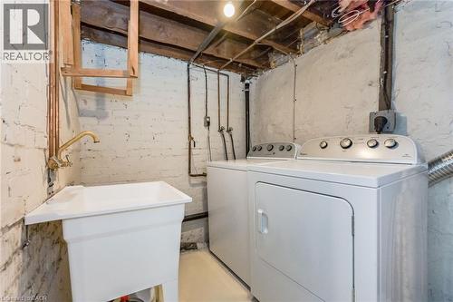 Laundry area featuring a utility sink with brass faucet, washer, and dryer - 67 Ahrens Street W, Kitchener, ON 