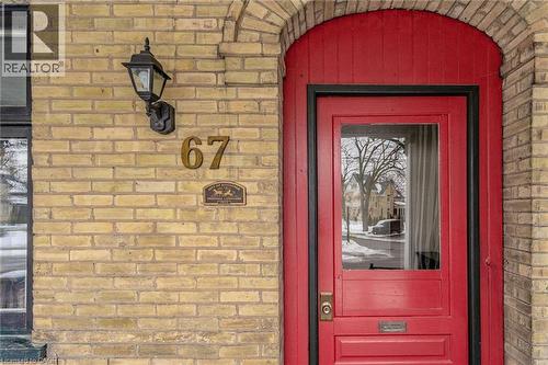 Vibrant red front door with a clear glass insert set within a brick arched entryway - 67 Ahrens Street W, Kitchener, ON 