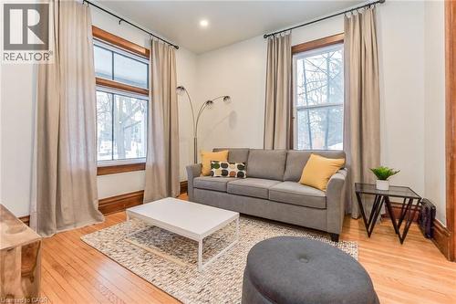 Bright living area featuring wood-finish flooring, white walls, and substantial wood window trim - 67 Ahrens Street W, Kitchener, ON 