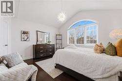 Bedroom featuring vaulted ceiling, dark wood-style floors, multiple windows, and suspended lighting - 