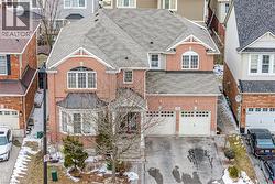 View of front of home featuring roof with shingles, driveway, a garage, and brick siding - 