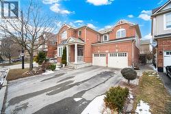 Traditional home with driveway, brick siding, and an attached garage - 