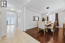 Dining space with wood finished floors, a tray ceiling, french doors, and ornate columns - 
