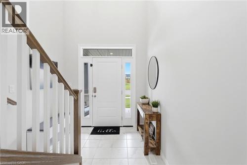 Bright foyer featuring a staircase with wood-finish handrail, white balusters, and a white entry door with sidelight and transom window - 39 Dunning Way, St. Thomas, ON 