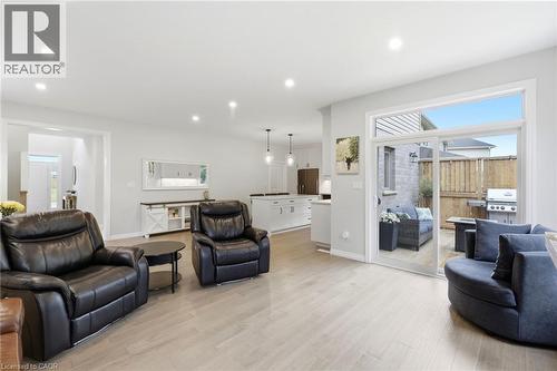 Expansive living area with wood-finish flooring, recessed lighting, and a sliding glass door opening to a private patio - 39 Dunning Way, St. Thomas, ON 