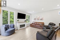 Living area featuring light wood-finish flooring, recessed lighting, and a white fireplace mantel with a light wood top - 