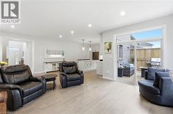 Expansive living area with wood-finish flooring, recessed lighting, and a sliding glass door opening to a private patio - 