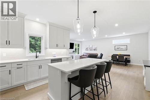 Modern kitchen featuring white cabinetry, a large center island with seating, pendant lighting, white countertops, and a subway tile backsplash - 39 Dunning Way, St. Thomas, ON 