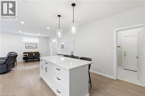 Kitchen island with white cabinetry, a light-toned countertop, and clear pendant lighting - 39 Dunning Way, St. Thomas, ON 