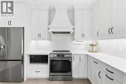 Contemporary kitchen featuring white shaker cabinetry, stainless steel appliances, and sleek countertops - 