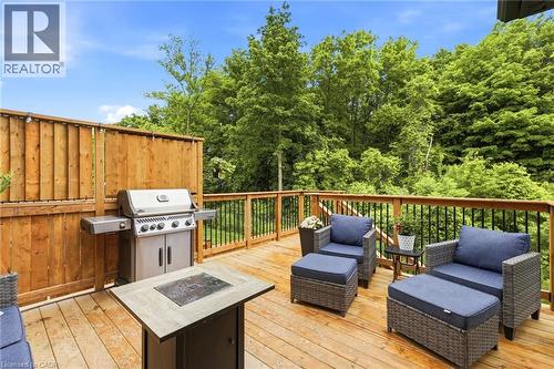 Expansive wood-finish deck featuring a full privacy fence, wood railings with black balusters, and a built-in outdoor grill - 39 Dunning Way, St. Thomas, ON 