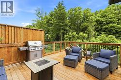 Expansive wood-finish deck featuring a full privacy fence, wood railings with black balusters, and a built-in outdoor grill - 