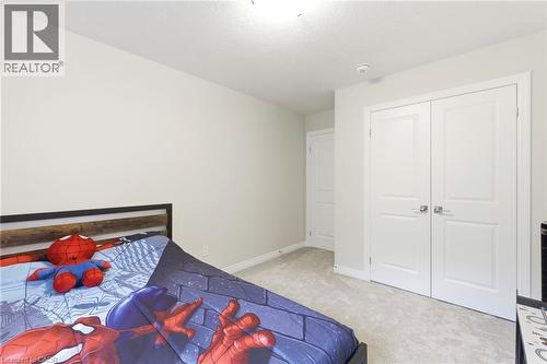 Carpeted room featuring light-colored walls, a prominent double-door closet with panel detailing and chrome hardware, and an additional white paneled door - 39 Dunning Way, St. Thomas, ON 