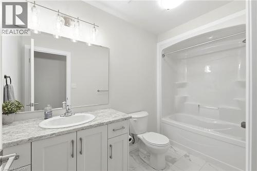 Bathroom featuring a white vanity with an oval basin sink, patterned countertop, and a wide mirror - 39 Dunning Way, St. Thomas, ON 