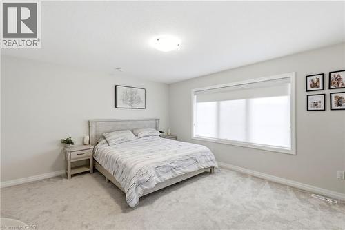 Bright room featuring light grey walls, plush grey carpeting, a large window with roller shades, and a ceiling-mounted light fixture - 39 Dunning Way, St. Thomas, ON 