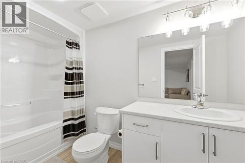 Bathroom featuring a shower-tub combination, single vanity with a white countertop, chrome faucet, and wood-finish flooring - 39 Dunning Way, St. Thomas, ON 