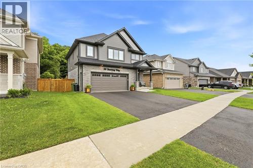 Modern two-story residence featuring a two-car garage, gray siding, and a partial stone facade - 39 Dunning Way, St. Thomas, ON 