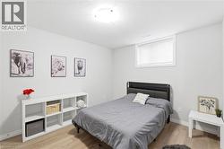 Well-lit room featuring light neutral wall paint, wood-finish flooring, and a window with blinds - 