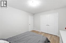 Bedroom featuring light wood-finish flooring, light grey painted walls, and white trim - 